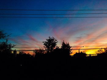 Silhouette of electricity pylon at sunset