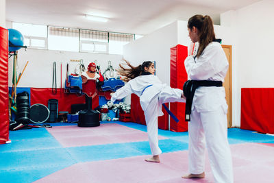 Full length of woman practicing martial art at gym