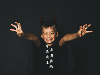 Portrait of boy standing against black background