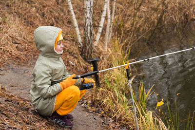 Side view of child holding hat on land