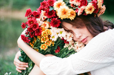 Mid adult woman with colorful flowers napping in forest