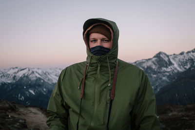 Portrait of young man standing against mountain during winter