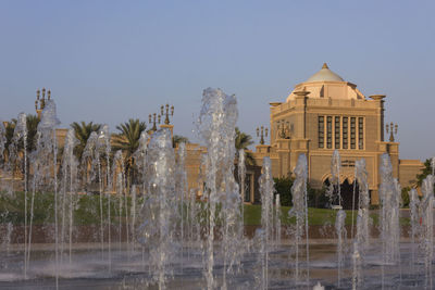 Fountain in front of building against clear sky