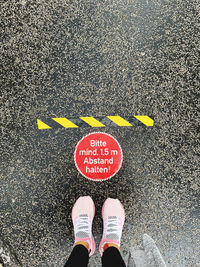 Low section of person standing on road sign