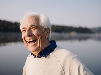 Man laughing while standing against lake