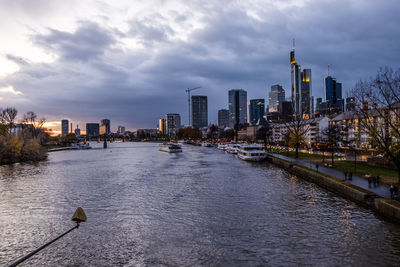 City at waterfront against cloudy sky