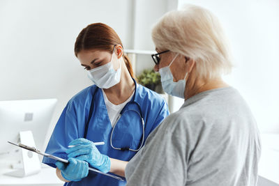 Female doctor wearing mask examining patient at clinic