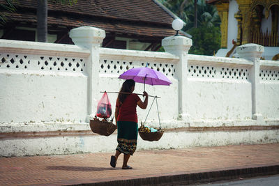 Full length of woman walking on footpath during rainy season