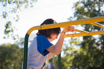 Rear view of girl playing on playground against sky