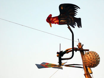 Low angle view of rooster flying against clear sky