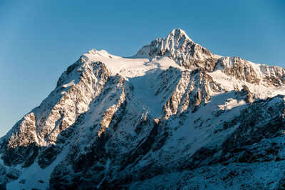 Scenic view of snowcapped mountains against clear blue sky