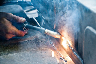 Cropped hand of welder welding metal in factory