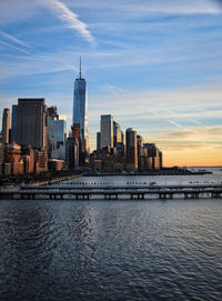 View of city at waterfront against cloudy sky