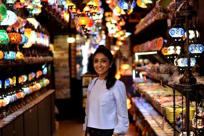 Portrait of smiling woman standing at lighting store