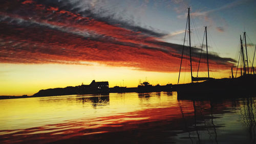 Silhouette sailboats in lake against sky during sunset