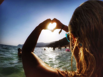 Woman hand in sea against clear sky