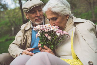 Senior couple holding bouquet sitting outdoors