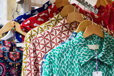 Close-up of multi colored shirts in coathangers hanging for sale at store