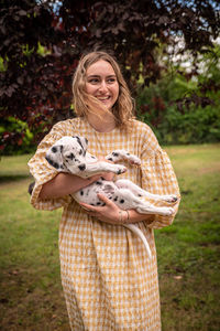 Portrait of smiling young woman standing against trees