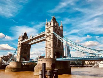 Tower bridge over thames river in city on sunny day