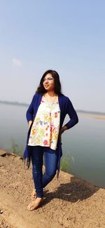 Full length of woman standing at beach against sky