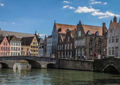 Bridge over river by buildings against sky in city