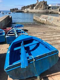 Fishing boat moored on beach against sky