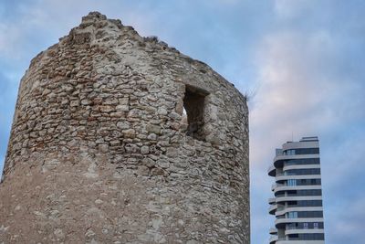 Low angle view of old building against cloudy sky