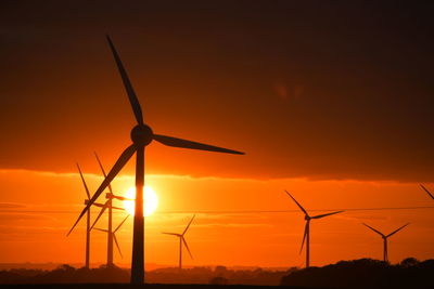 Silhouette windmill on landscape against sky during sunset