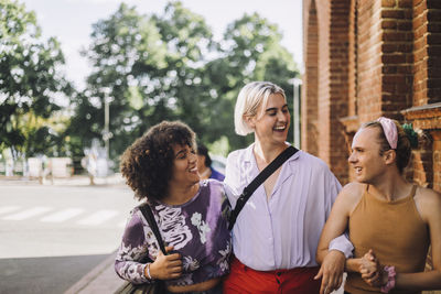 Smiling young woman walking with non-binary friends