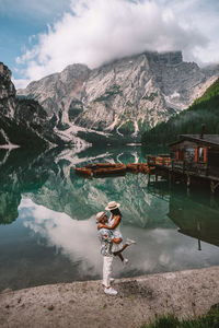 Woman standing by lake against sky