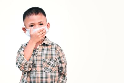 Portrait of boy standing against white background