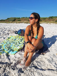 Caucasian girl with braids sunbathes on the sand in the dunes of white beach in rosignano tuscany