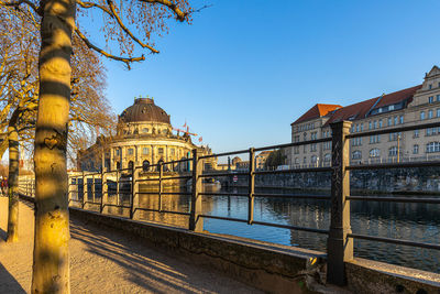 View of river by buildings against clear sky