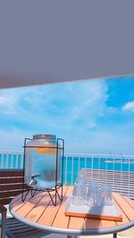 Chairs and table by swimming pool against sky