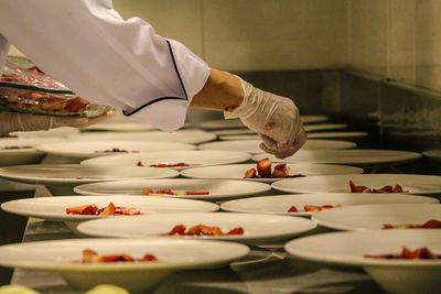 Cropped hand of chef arranging dessert on plates at kitchen