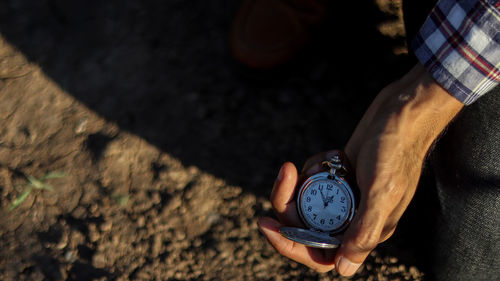 High angle view of hand holding clock