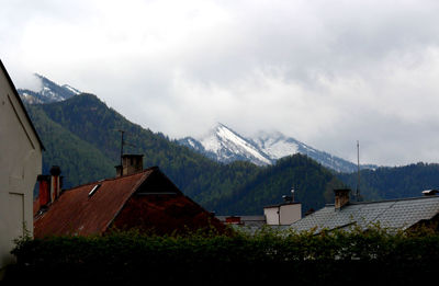 Houses on mountain against cloudy sky