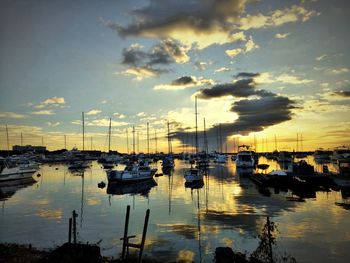 Boats moored at harbor during sunset