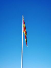 Low angle view of flag against clear blue sky