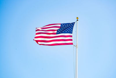 Low angle view of flag against blue sky