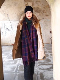 Portrait of young woman standing against wall