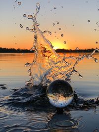 Close-up of water splashing on lake against sky during sunset