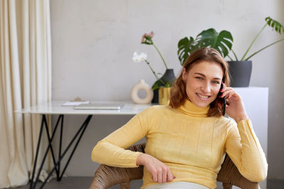 Portrait of smiling woman sitting at home