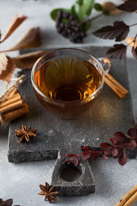 Delicious freshly brewed aromatic tea in a glass cup with a board and various natural ingredients. 