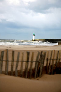 Lighthouse on beach against sky