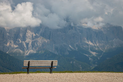 Empty bench on snowcapped mountains against sky