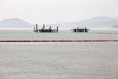 Floating platforms and buoys on sea against clear sky