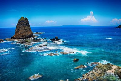 Scenic view of rocks in sea against blue sky