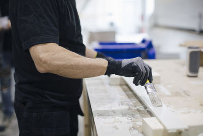 Senior worker painting wooden box while standing in industry